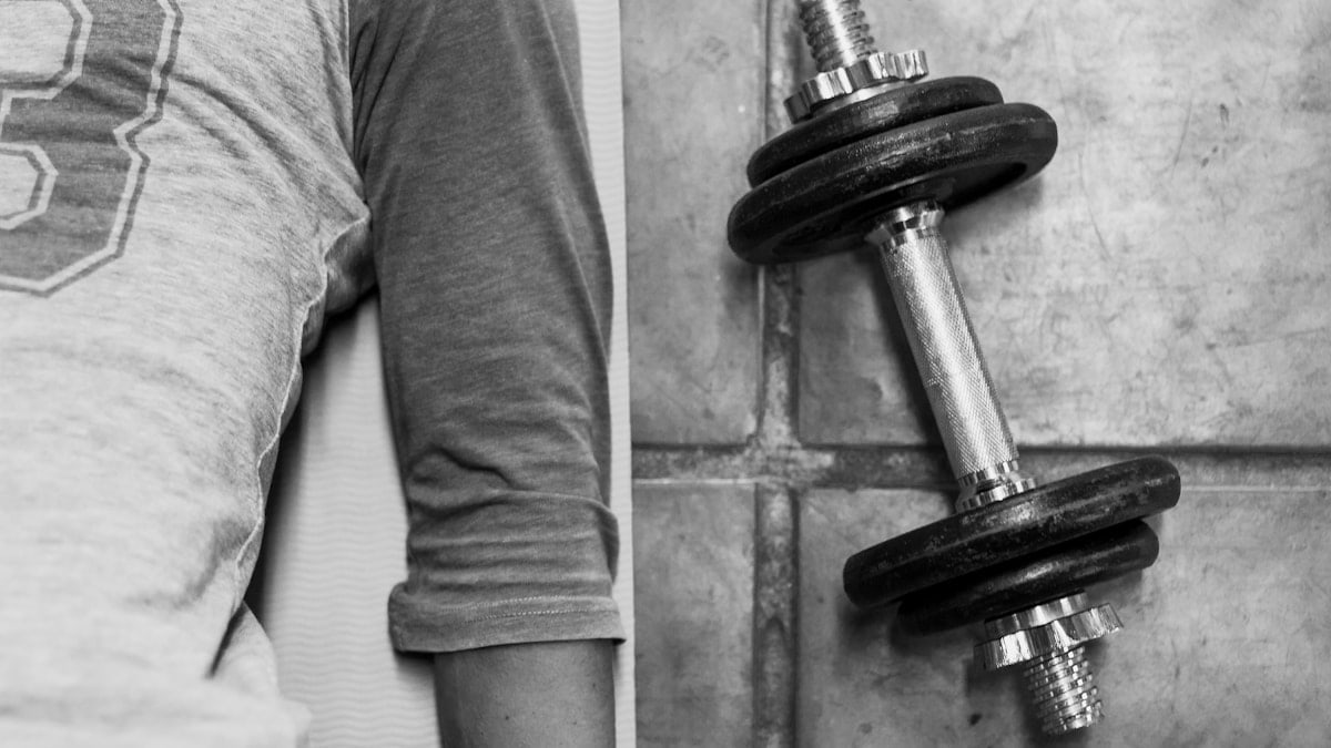 person in black pants and black socks holding dumbbell